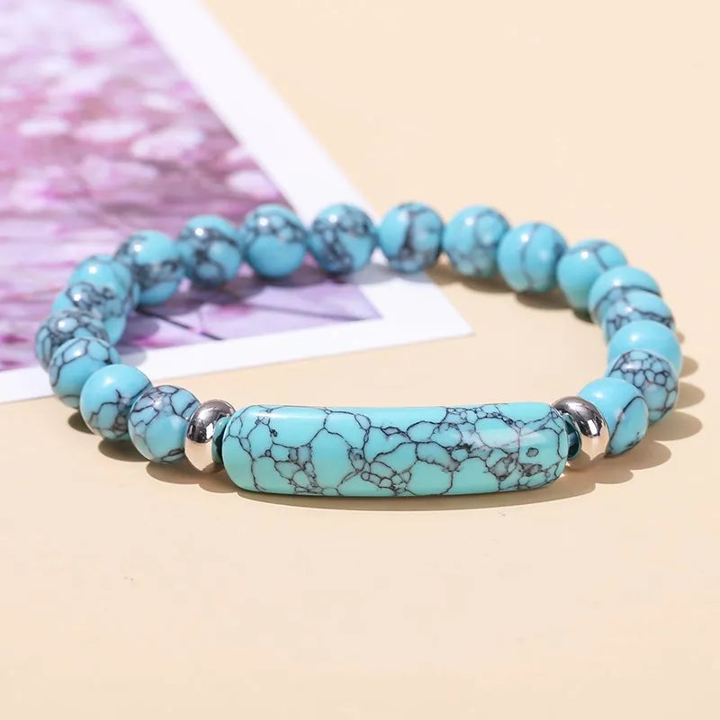 Turquoise beaded bracelet with silver accents on a beige surface