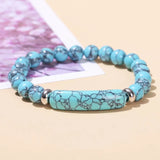 Turquoise beaded bracelet with silver accents on a beige surface