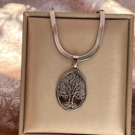 Silver necklace with a tree pendant on a beige box