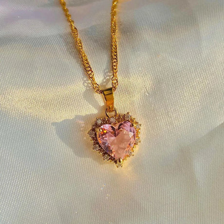 Heart-shaped pink gemstone pendant on a gold chain against a light background