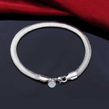 Silver bracelet with a round charm on a dark surface with red fabric in the background