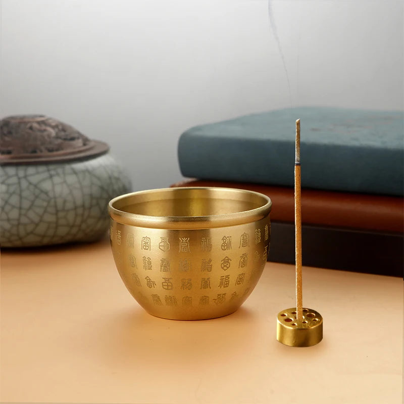 Brass incense burner with incense stick on a wooden surface