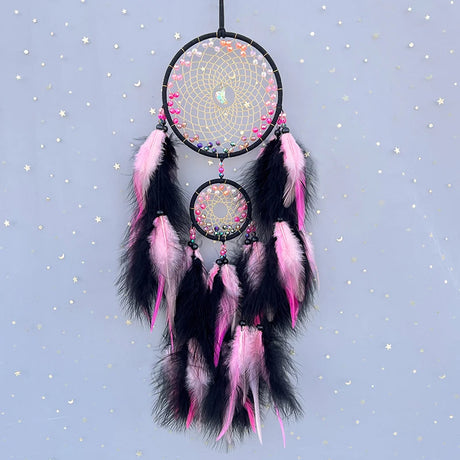 Decorative dreamcatcher with pink and black feathers on a starry background