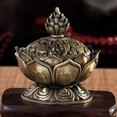 Decorative bronze incense burner with intricate designs on a wooden stand.