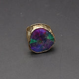 Gold ring with a colorful stone on a gray background