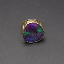 Gold ring with a colorful stone on a gray background