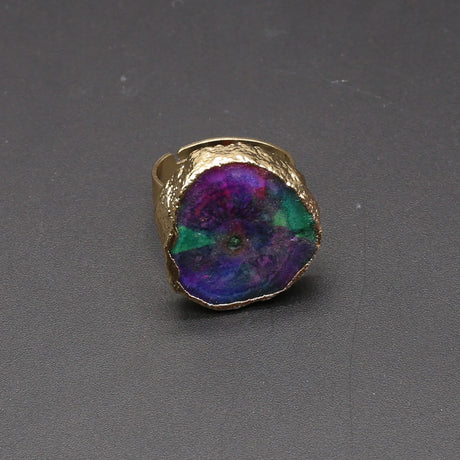 Gold ring with a colorful stone on a gray background