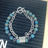 Bracelet with blue and silver beads on a textured black background