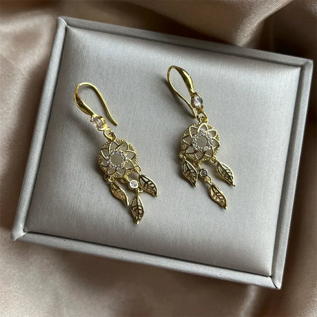 Gold earrings on a gray jewelry box with a beige fabric background