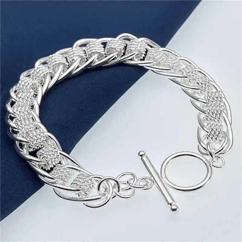 Silver bracelet with intricate design on a blue and white striped background