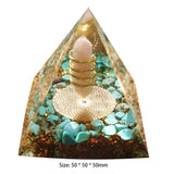 Pyramid-shaped object with a candle inside, surrounded by turquoise stones on a white background.