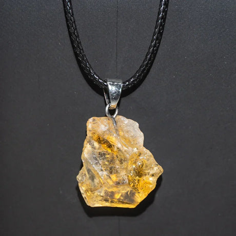 Crystal pendant on a black cord against a dark background