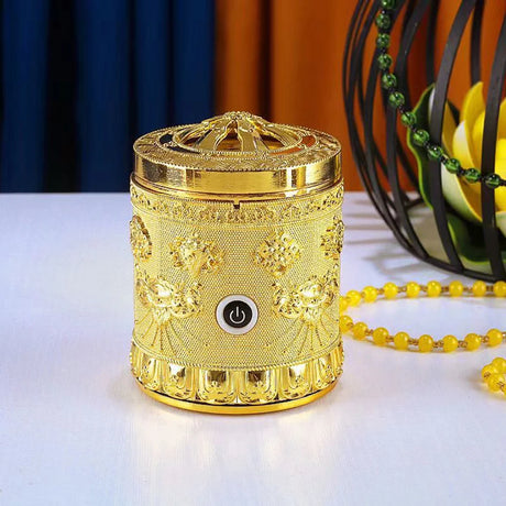 Decorative gold incense burner with power button on a white surface