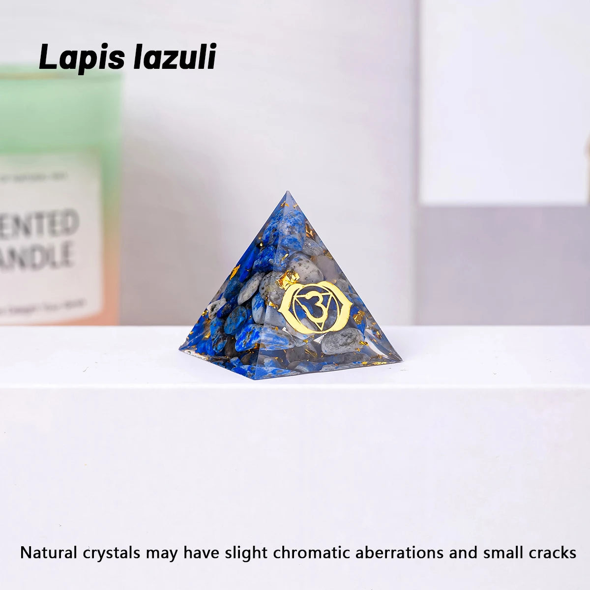 Pyramid-shaped lapis lazuli crystal with a gold emblem on a white surface.