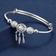 Silver bracelet with decorative beads and feathers on a blue background