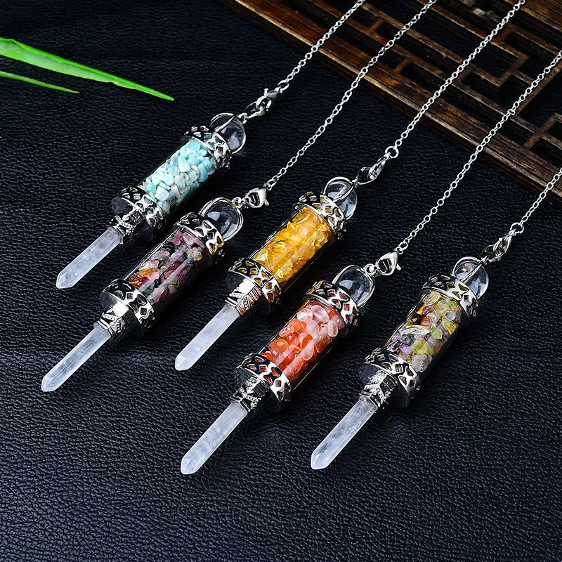 Five crystalpendants on chains with embedded stones on a dark textured surface.