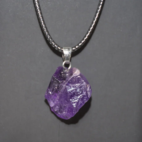 Purple crystal pendant on a silver chain against a gray background