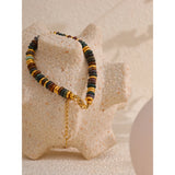 Multicolored beaded bracelet with a gold chain on a textured beige surface