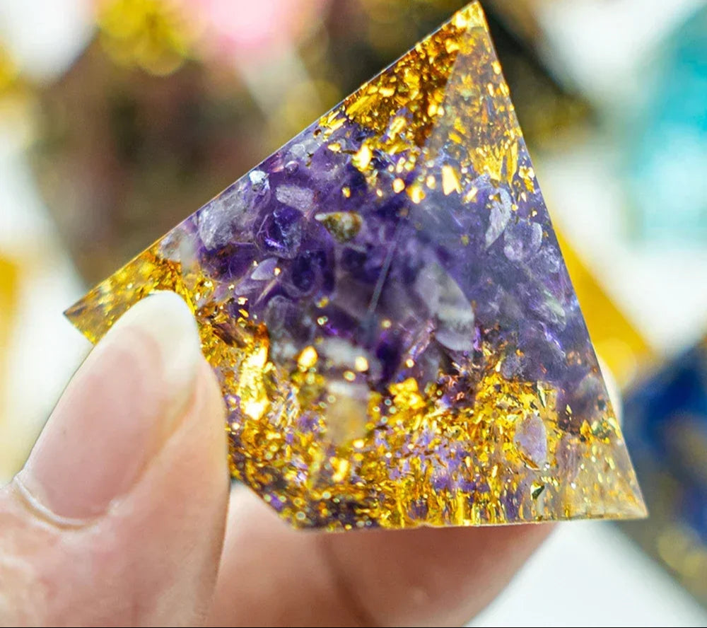 Triangular crystal with purple and gold interior held by a hand, brand 'AierCrystal' visible.
