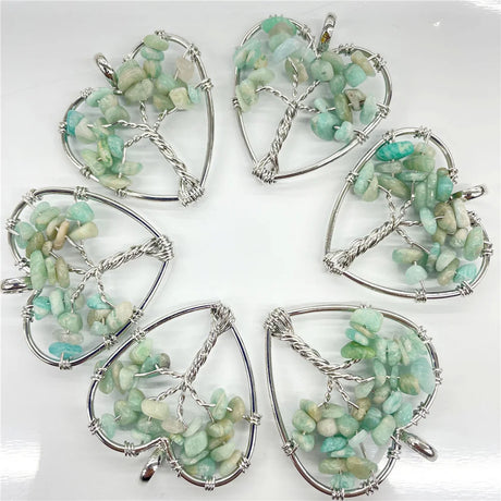 Five heart-shaped pendants with green stones and silver wire wrapping on a white background
