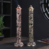 Two intricately designed incense sticks on a dark surface with a blurred background