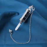 Decorative syringe-shaped object with a chain on a blue fabric background