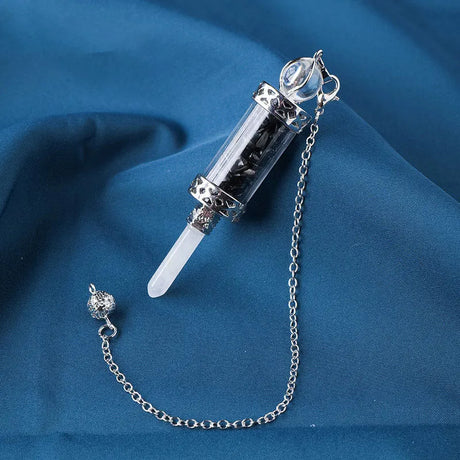 Decorative syringe-shaped object with a chain on a blue fabric background