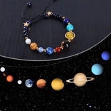 Bracelet with colored beads resembling planets on a black background with planet illustrations.