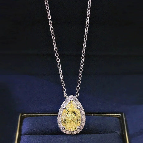 Teardrop-shaped yellow diamond pendant on a silver chain against a dark background