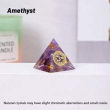 Amethyst pyramid with gold 'Om' symbol on a white surface, with a blurred background.
