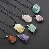 Necklaces with raw crystal pendants on a dark surface