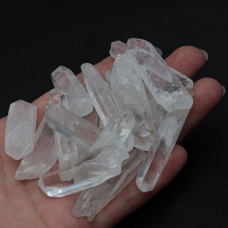 Hand holding a collection of clear crystal points against a dark background