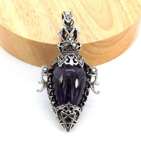 Decorative pendant with purple stone and silver design on a wooden surface