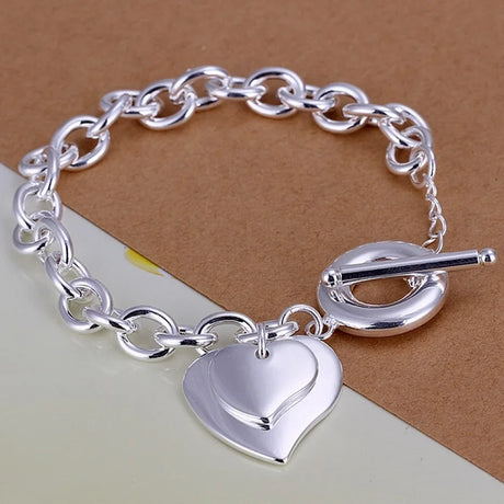 Silver chain bracelet with a heart-shaped charm on a brown background
