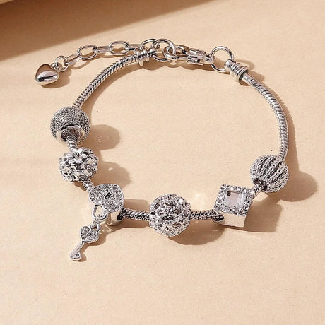 Silver bracelet with various charms on a beige background