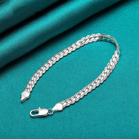 Silver chain bracelet on a teal fabric background