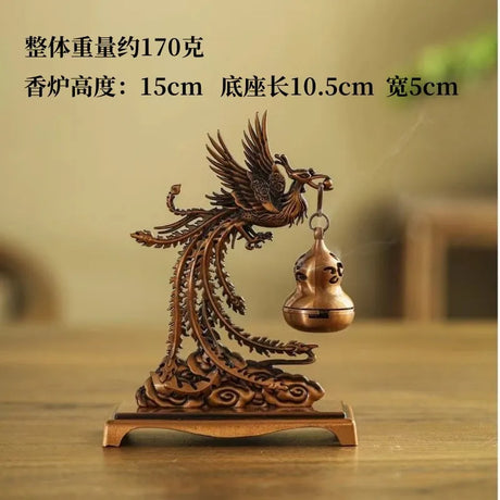 Bronze phoenix sculpture with a bell on a wooden surface