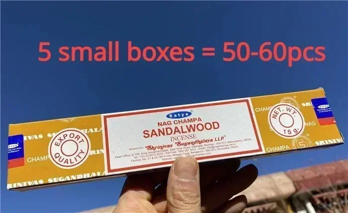 Nag Champa Sandalwood incense stick box held by a hand with text overlay on a blue sky background.