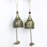 Two brass bells with fish charms on a white background