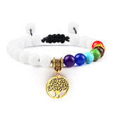 Bracelet with white beads, colorful beads, and a gold tree-of-life charm on a white background