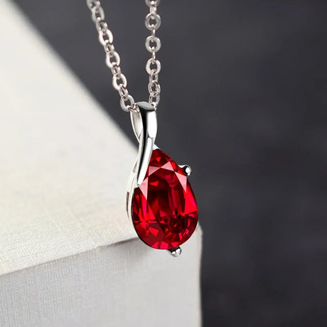 Red teardrop pendant on a silver chain against a neutral background
