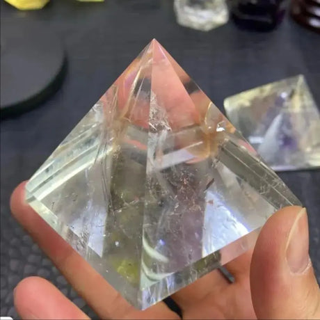 Clear crystal pyramid held in a hand with a blurred background