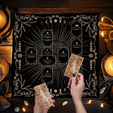 Person holding tarot cards in front of a decorative black and white tarot card layout with candles and stones on a wooden surface.