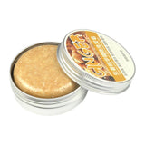 Open tin of beige-colored cream with a label on a white background