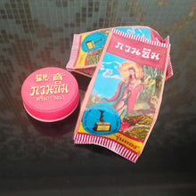Pink container with a colorful label featuring religious iconography on a reflective surface.