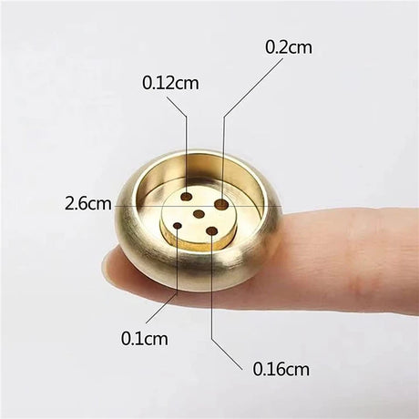 Gold-colored circular object held between fingers with measurements labeled
