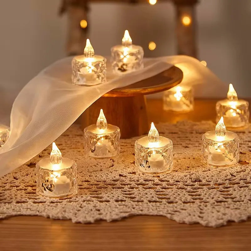 Small lit candles in glass holders on a lace tablecloth with a warm glow.