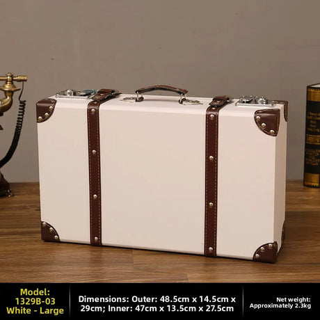White suitcase with brown straps on a wooden surface