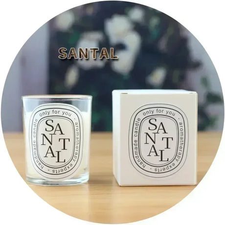 Santal candle and packaging on a wooden surface with a blurred floral background