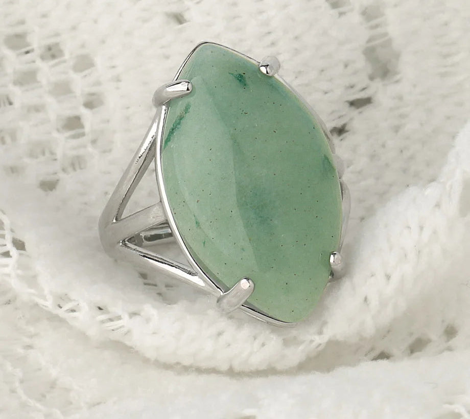Silver ring with a green stone on a textured white background